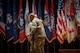 two men hug in front of flags wearing u.s. army uniform.