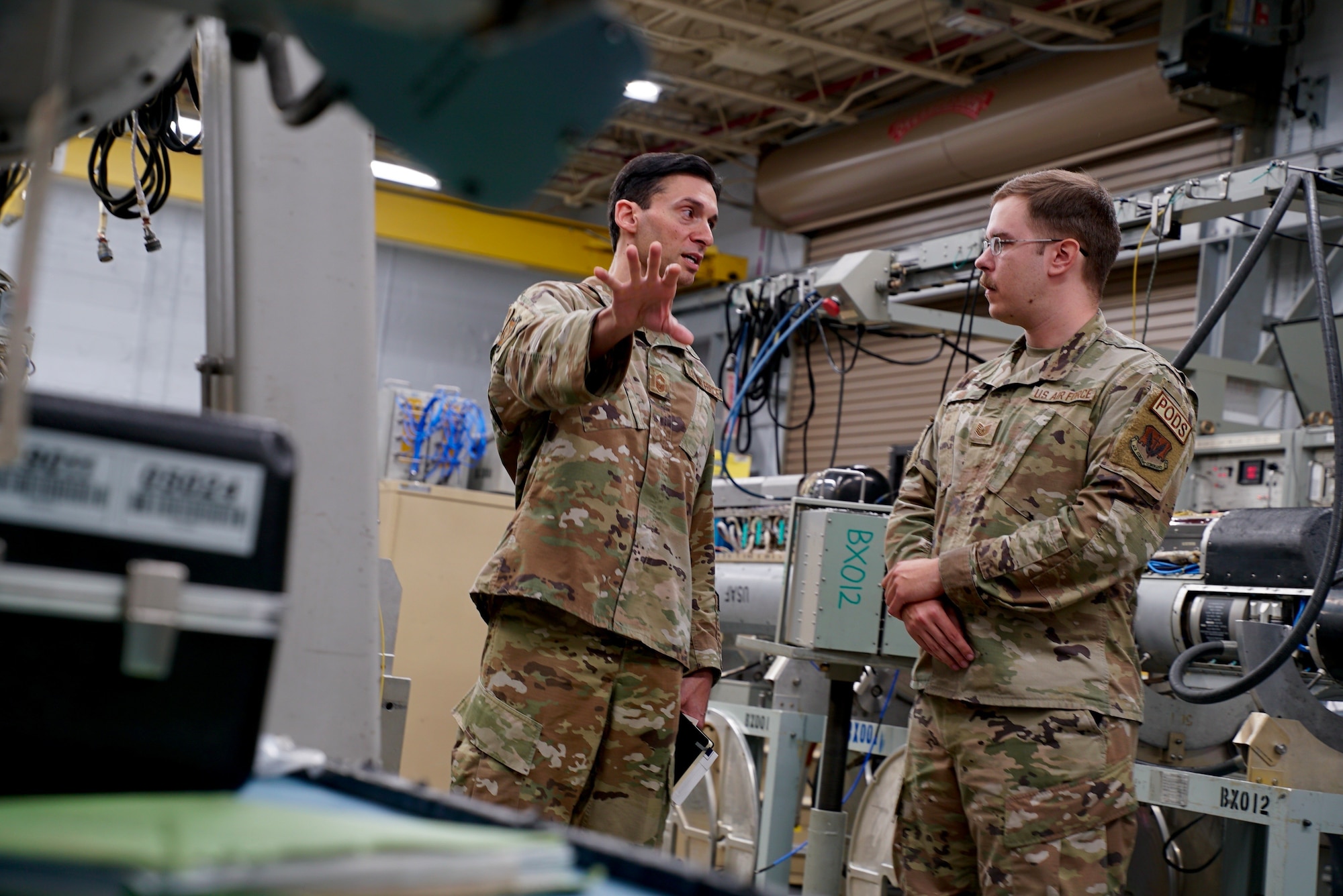 U.S. Air Force Chief Master Sgt. Israel Jaeger, senior enlisted advisor for intelligence, surveillance, reconnaissance, and cyber effects operations, talks with Tech. Sgt. Garrett Fox, 36th Electronic Warfare Squadron pod maintenance NCOIC, about the mission of the Pod Shop at Eglin Air Base, Fla., Feb. 1, 2023. Jaeger was part of a wing visit to the 350th Spectrum Warfare Wing and during his visit to the Pod Shop, learned how the pods use the Electromagnetic Spectrum to jam, deny, and deceive enemy radar systems to effectively protect aircraft from radar guided missiles. (U.S. Air Force photo by 1st Lt. Benjamin Aronson)