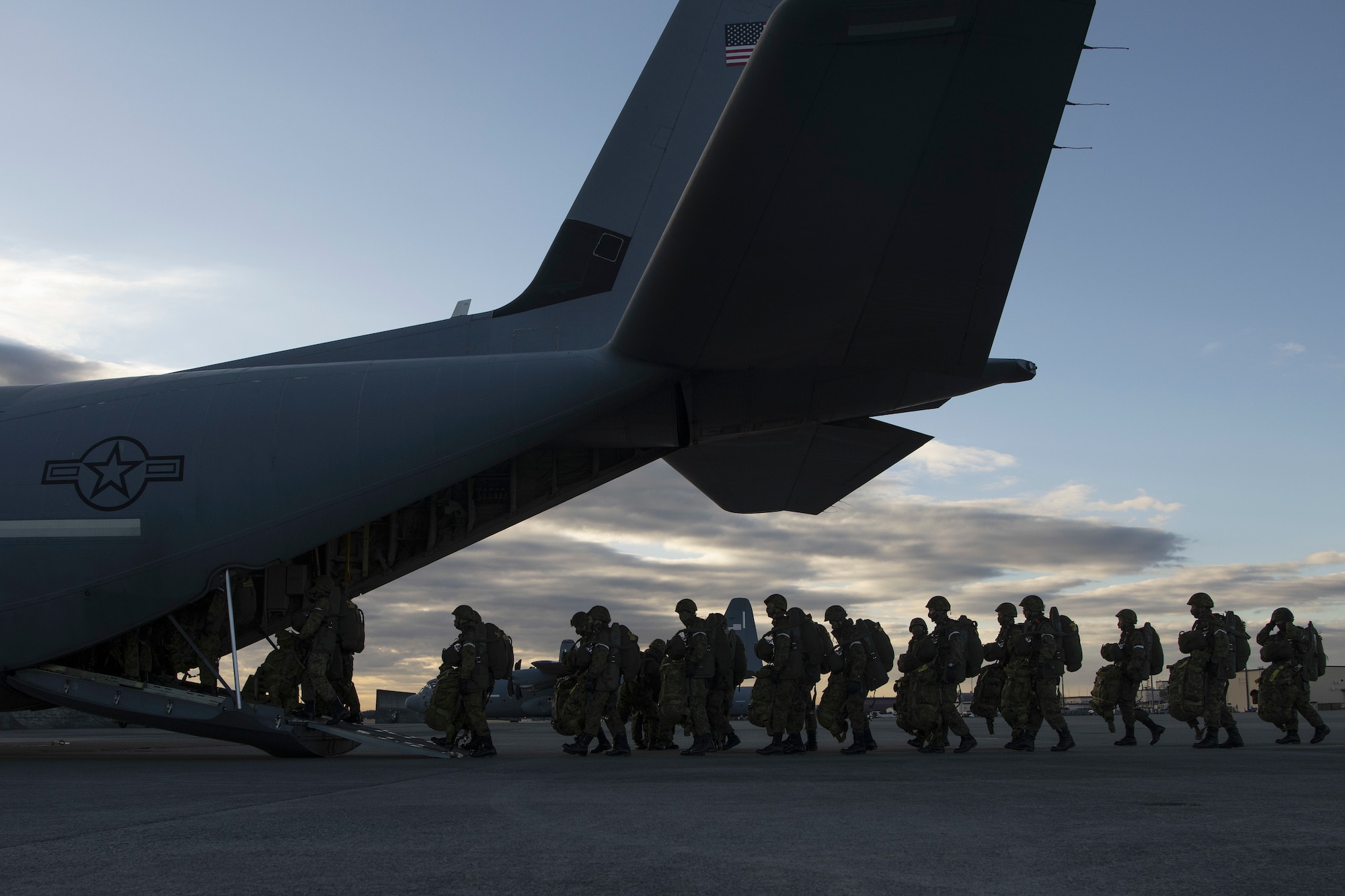 Japanese soldiers march onto a cargo aircraft via the rear cargo ramp