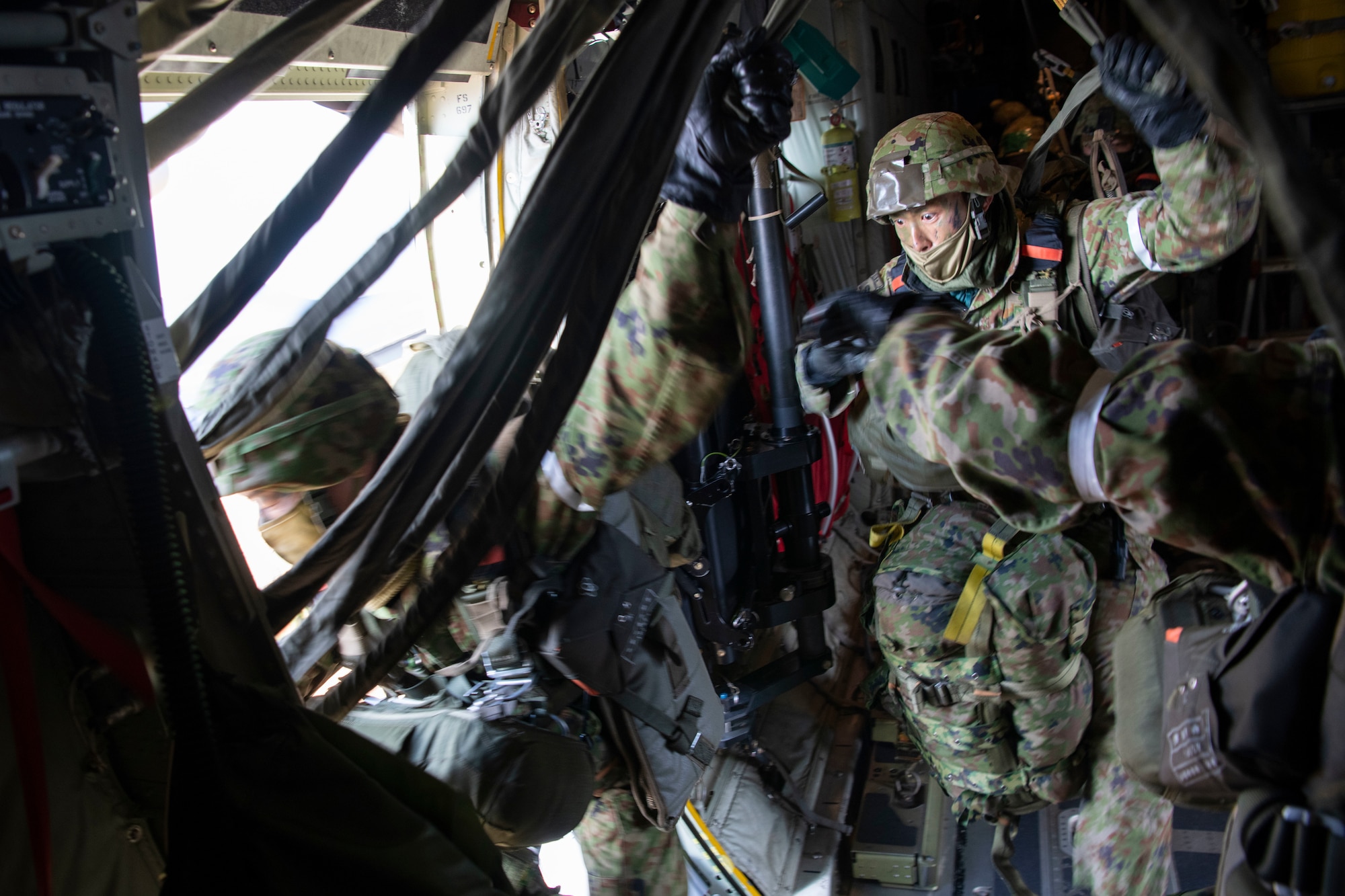 Japanese soldiers jump out the side door of a military plane