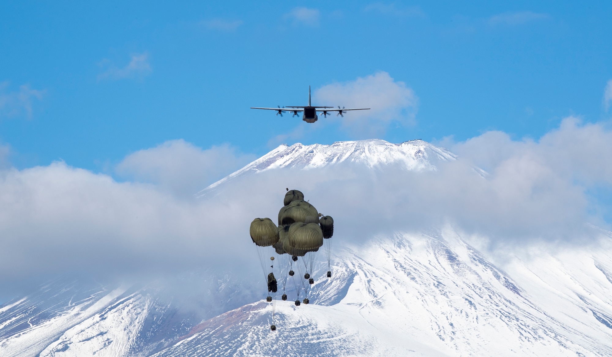 Japan Ground Self-Defense Force's heavy containerized delivery system (CDS) bundles drop from a U.S. Air Force C-130J Super Hercules assigned to the 36th Airlift Squadron at JGSDF East Fuji Maneuver Area, Japan, Jan. 31, 2023, during Airborne 23. Nine C-130J aircraft assigned to Yokota Air Base and Little Rock Air Force Base, Arkansas, were used to carry approximately 300 JGSDF paratroopers and CDS bundles to drop zones at Higashi-Fuji training field during the static-line personnel jump portion of the exercise. Airborne 2023 is a large-scale airborne operation integrating air and ground forces from Japan and the United States. (U.S. Air Force photo by Yasuo Osakabe)