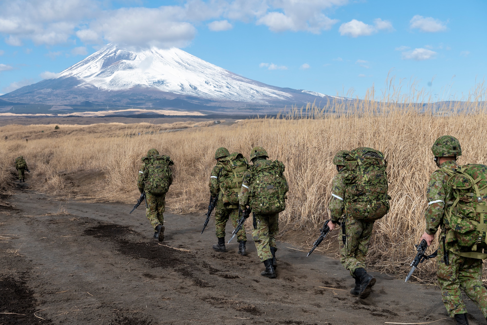 Japan Ground Self-Defense Force paratroopers assigned to the 1st Airborne Brigade move to follow-on locations after landing at JGSDF East Fuji Maneuver Area, Japan, Jan. 31, 2023, during Airborne 23. Nine C-130J aircraft assigned to Yokota Air Base and Little Rock Air Force Base, Arkansas, were used to carry approximately 300 JGSDF paratroopers to drop zones at Higashi-Fuji training field during the static-line personnel jump portion of the exercise. Airborne 2023 is a large-scale airborne operations integrating air and ground forces from Japan and the United States. (U.S. Air Force photo by Yasuo Osakabe)