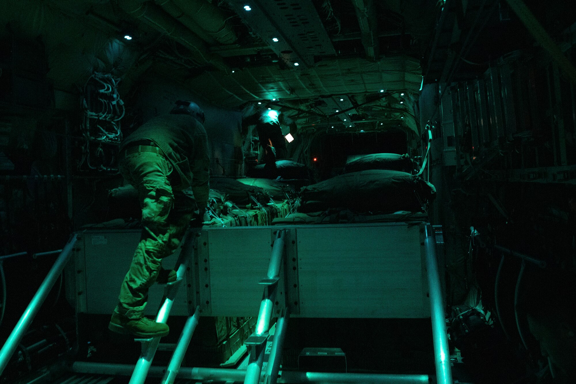 US Airmen check cargo boxes in the rear of a cargo plane