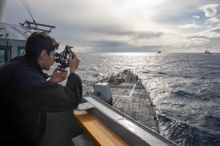 Quartermaster 3rd Class Charles Piloni, assigned to the Arleigh Burke-class guided-missile destroyer USS Nitze (DDG 94),  uses a sextant to get the bearing of the Italian Navy Alpino-class frégate européenne multi-mission frigate ITS Alpino (F 594), Jan. 11, 2023.