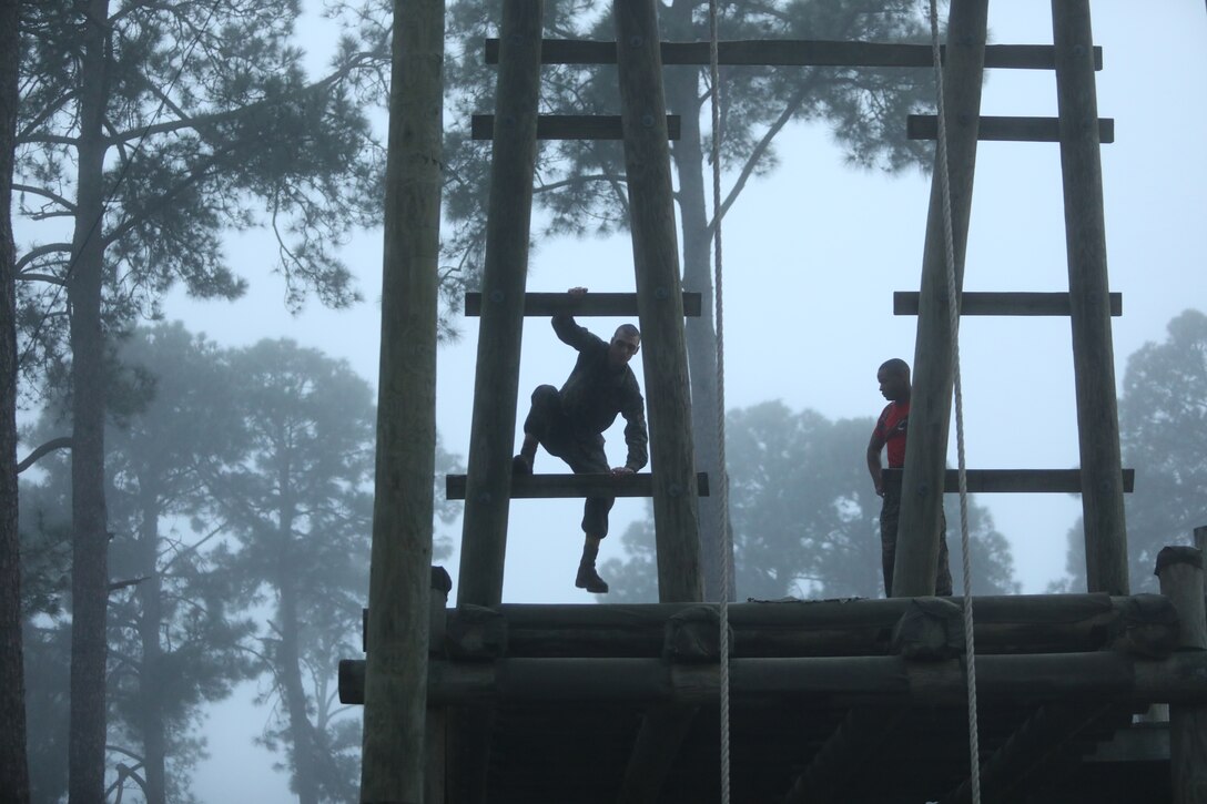 Marine Corps recruits climb a very large ladder.