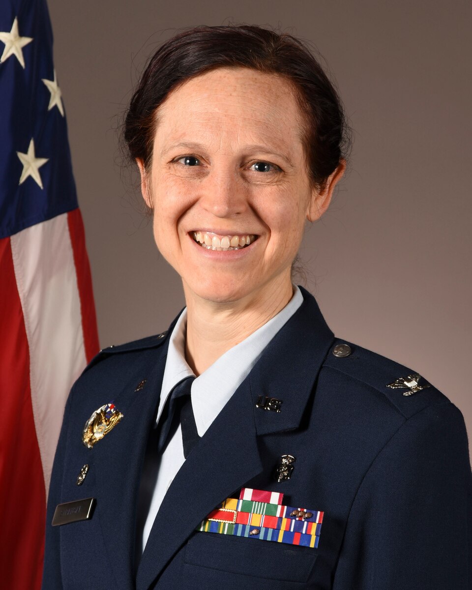 A woman in a blue uniform smiles for a photo.