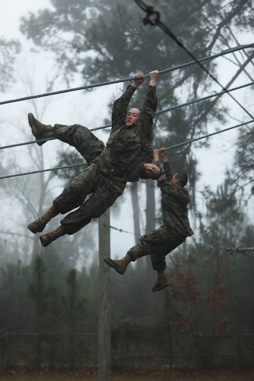 Marine Corps recruits swing from ropes.