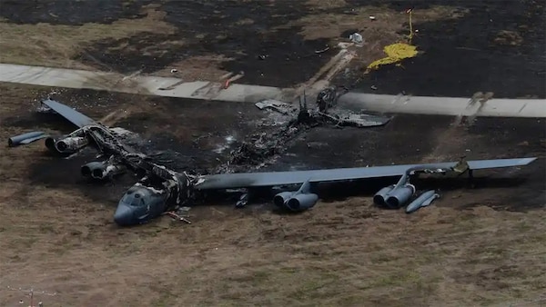 A destroyed B-52 bomber sits in a field.