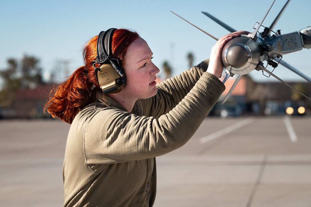 Close-up of a service member checking weapons on an aircraft.