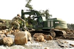 U.S. Army Pfc. Levi Walkup of the California Army National Guard’s 649th Engineer Company, 185th Military Police Battalion, 49th Military Police Brigade, traverses a trail of boulders he placed to shorten the route between his excavator and a mission planning area while working to reroute the San Ysidro Creek in the Randall Road Debris Basin in Montecito, California, Jan. 13, 2023.