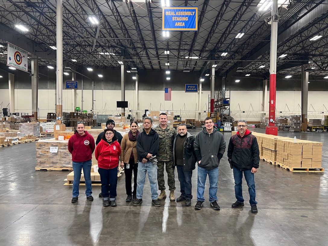 Marine Col. Kevin Chunn, commander of Defense Logistics Agency Distribution San Joaquin, California, and employees from the Unitized Group Rations mission pose for a photo during a celebration that recognized UGR mission’s 100th consecutive month of meeting the war reserve requirements