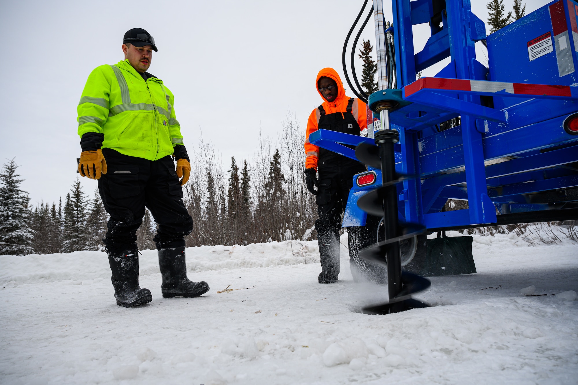 U.S. Air Force Staff Sgt. Dawson Templer, left, a 19th Civil Engineer Squadron structural craftsman, and Senior Airman Zachary Lynch, a 99th Civil Engineer Squadron pavements and construction journeyman, use a BH-18 ice drill on the ice bridge at the Blair Lake Range Complex, Alaska, Jan. 26, 2023.