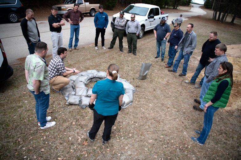 Matthew Collins, kneeling, emergency management chief, talks about the importance of flood-fighting techniques after a sandbag demonstration during dam safety training at the Richard B. Russell Dam on Feb. 1, 2023. USACE photo by Mel Orr.