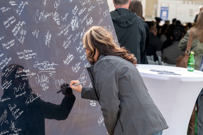 An Edwards Solar Enhanced Use Lease Project ribbon cutting ceremony attendee signs her name on the honorary solar panel commemorating the largest private-public collaboration in Department of Defense history at Edwards Air Force Base, California, Feb. 2.