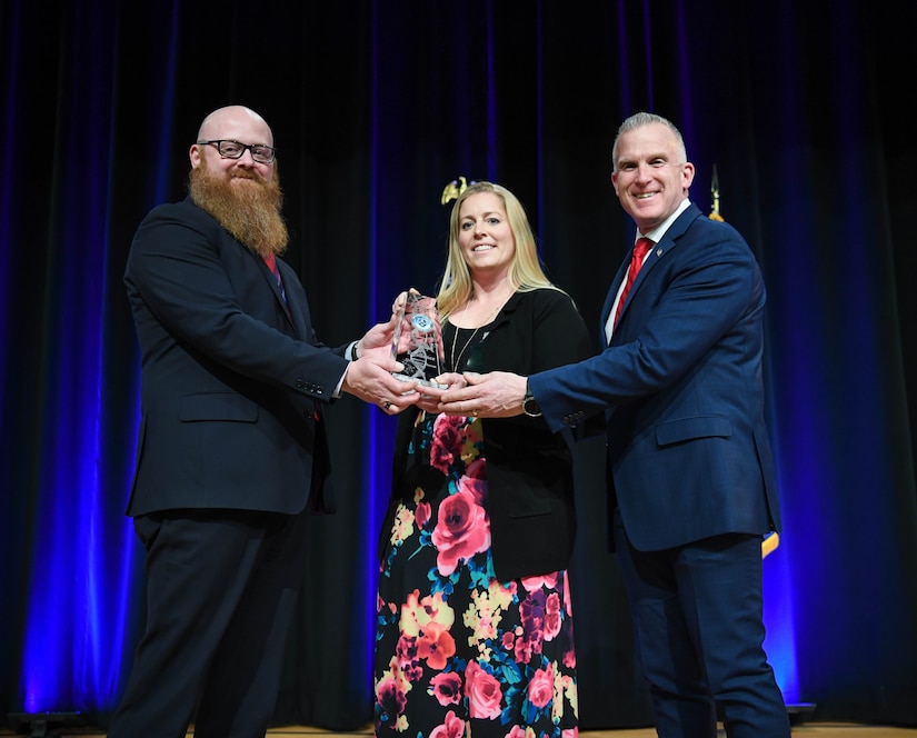 Three people are holding an award.