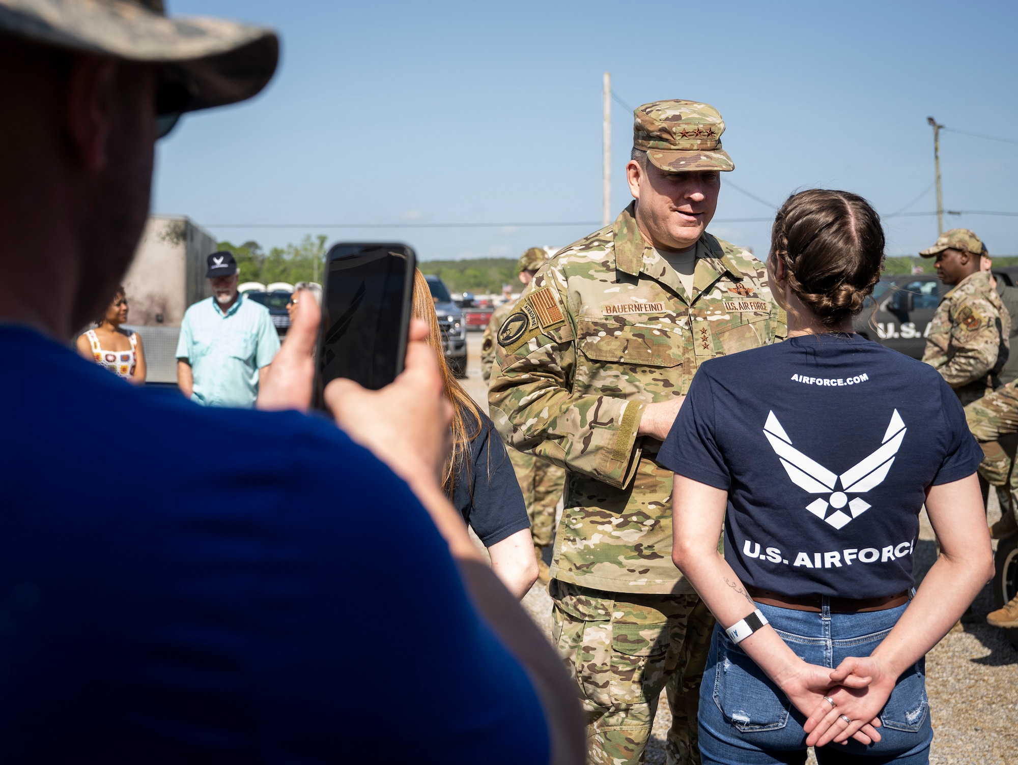 A proud parent records his daughter meeting her first general officer, Lt. Gen. Tony Bauernfeind, commander of U.S. Special Operations Command, during a recruitment event at Talladega Superspeedway, Ala., April 24, 2022. The general visited the NASCAR race where he performed a swearing-in ceremony for 14 future Airmen. Air Force Recruiting Service launched an expanded, redesigned version of airforce.com, Feb. 6, 2023. (U.S. Air Force photo by Samuel King Jr.)