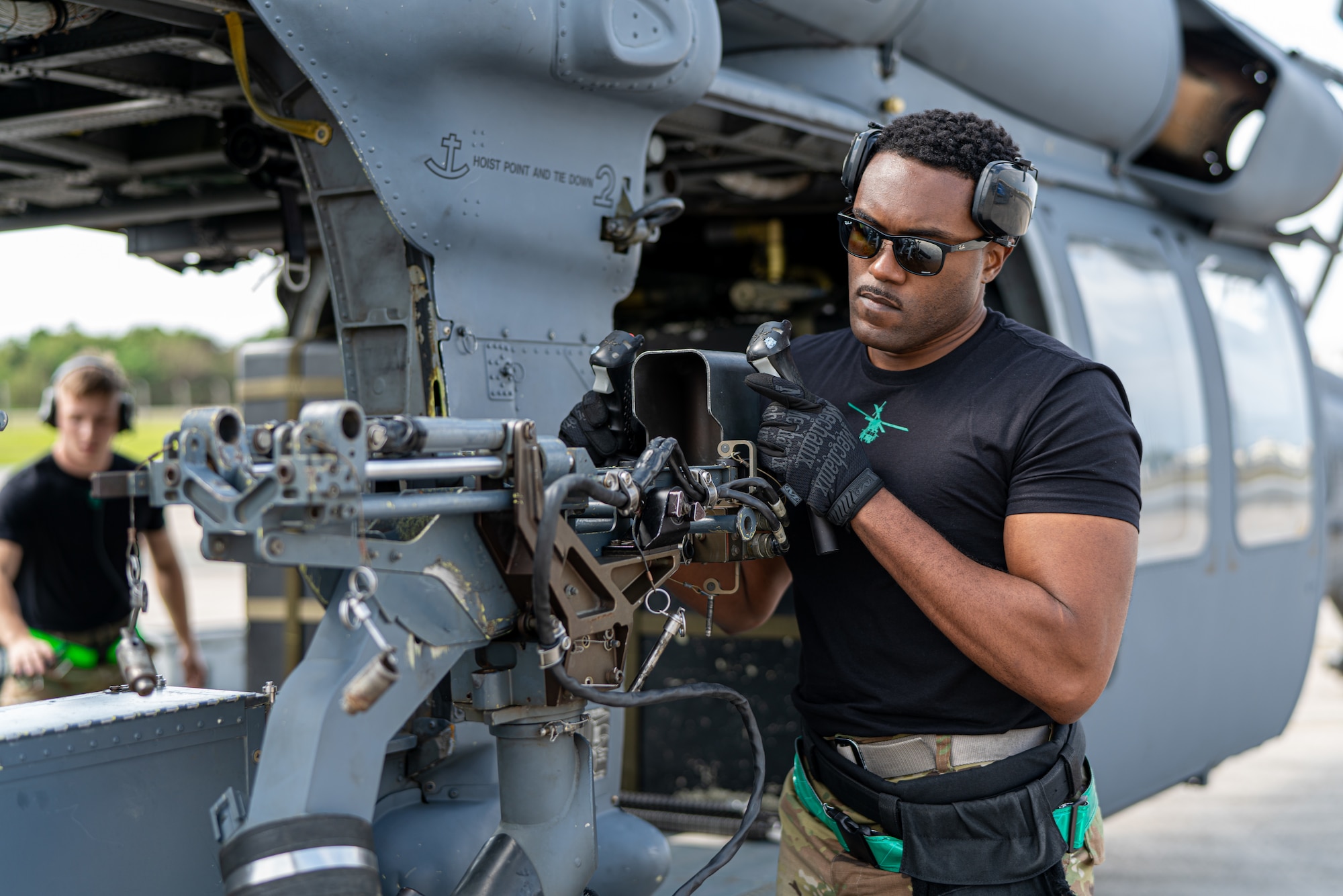 An Airman attaches a machine gun to a helicopter.