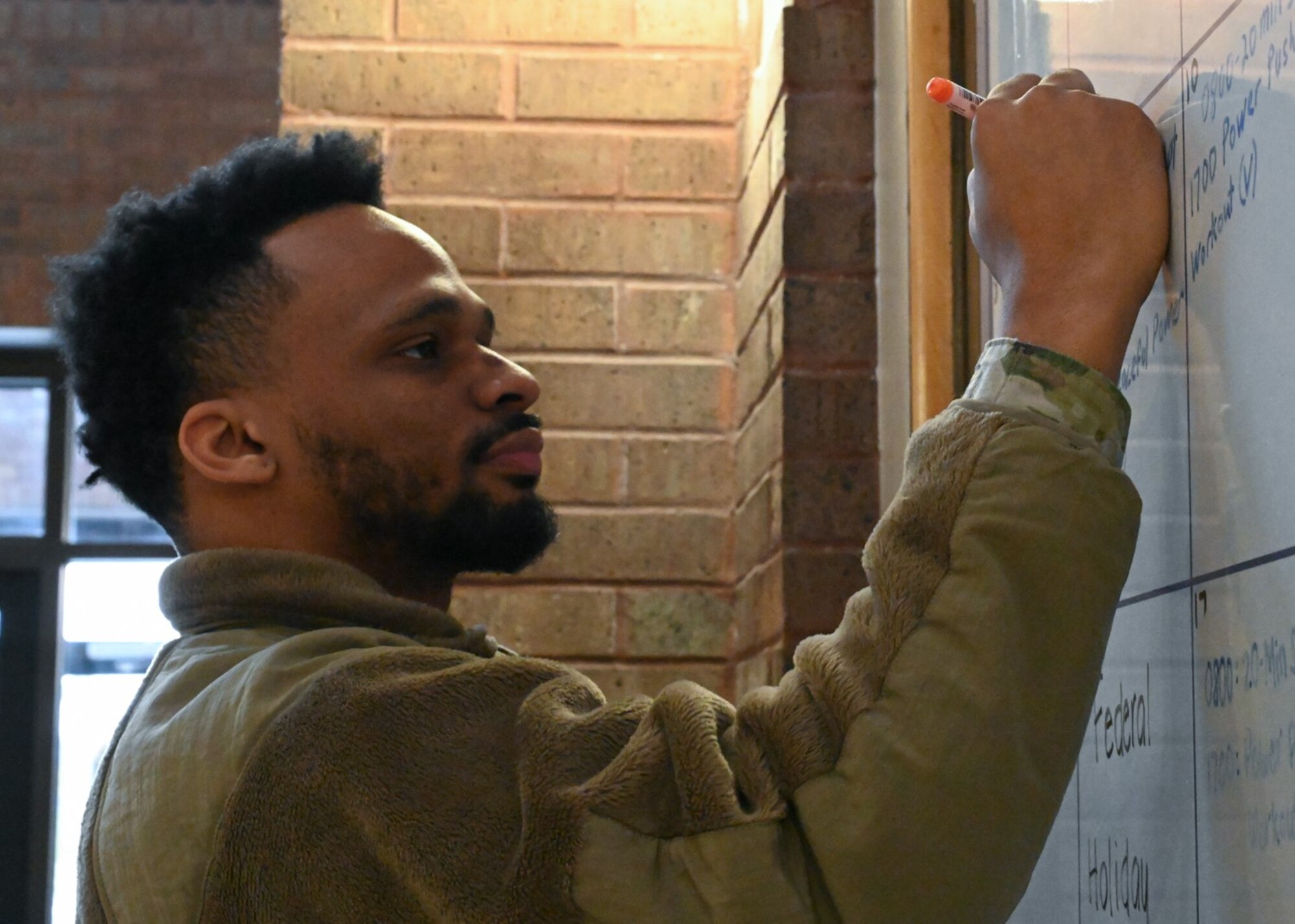 Senior Airman Zachary Holmes, Services Airman with the 509th Force Support Squadron,  Writes on the gym calendar at Whiteman Air Force Base, Missouri, January 20, 2023. Holmes shares the date and location events will be held on base for potential participants. (U.S Air Force photo by Senior Airman Nash Truitt)