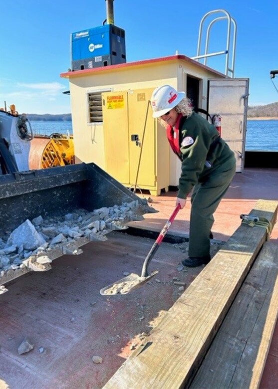 Judy Daulton stands on the surface of the PRIDE of the Cumberland barge shoveling away debris.