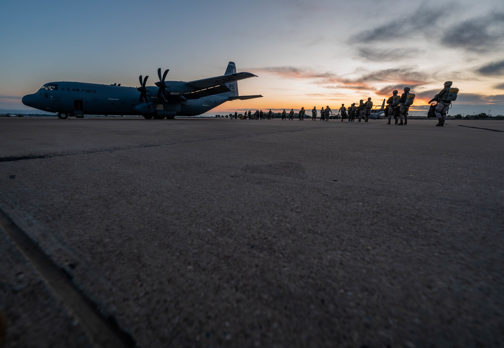 Spanish air force members line up behind a C-130J to board the aircraft.