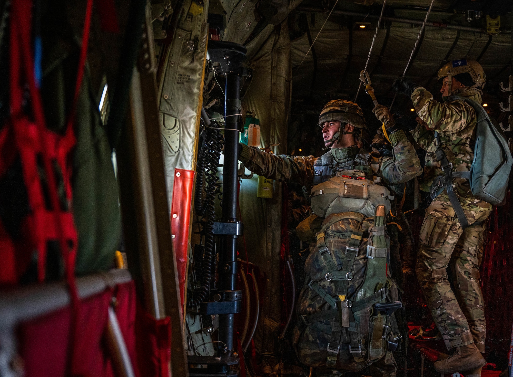 An Army paratrooper prepares to jump out of the side door of a C-130J.