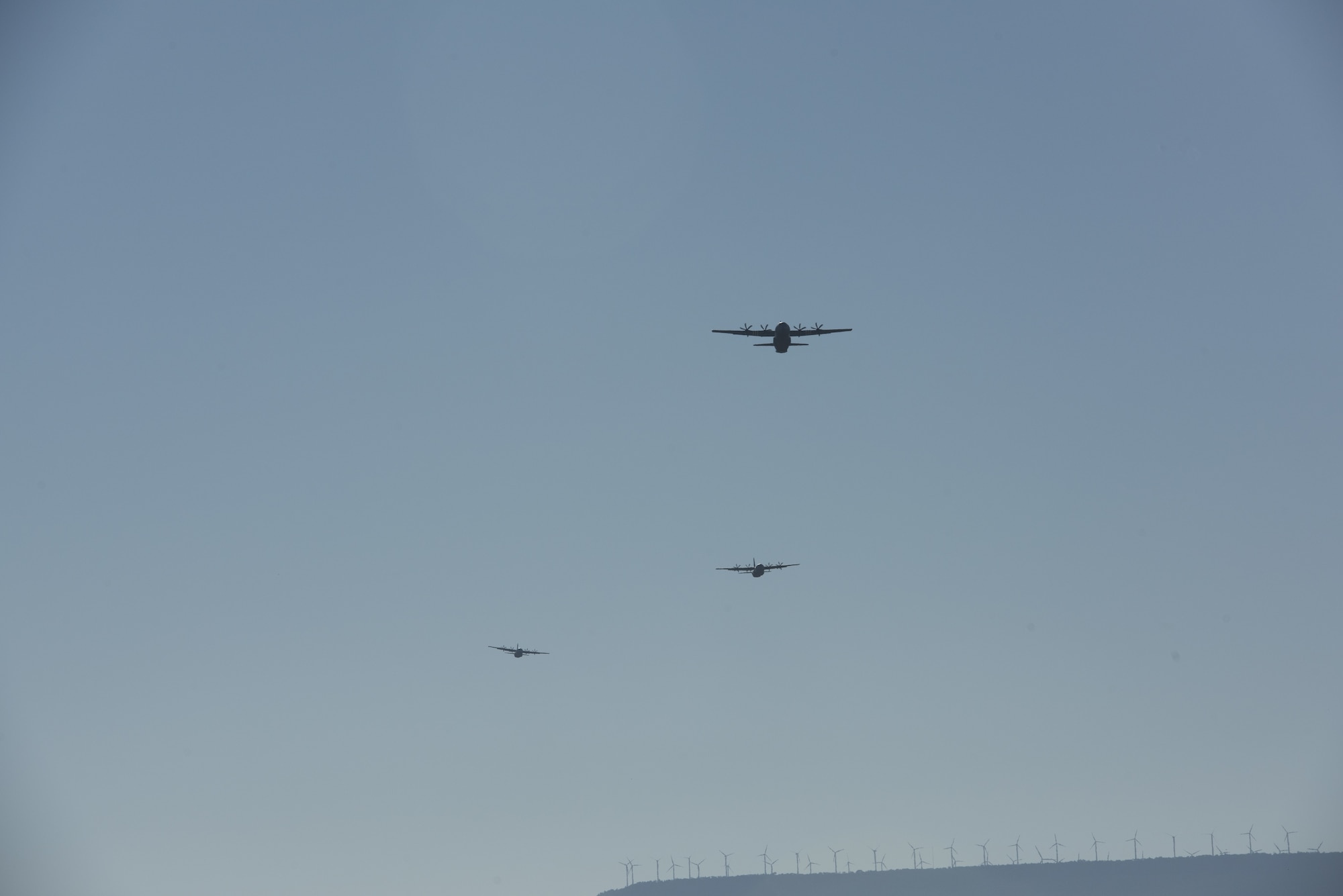 Three aircraft fly through a bright blue sky