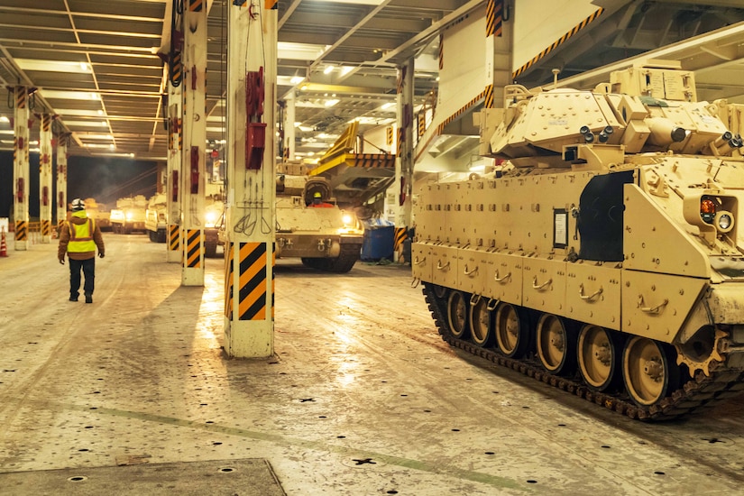 A man walks beside a row of tanks.