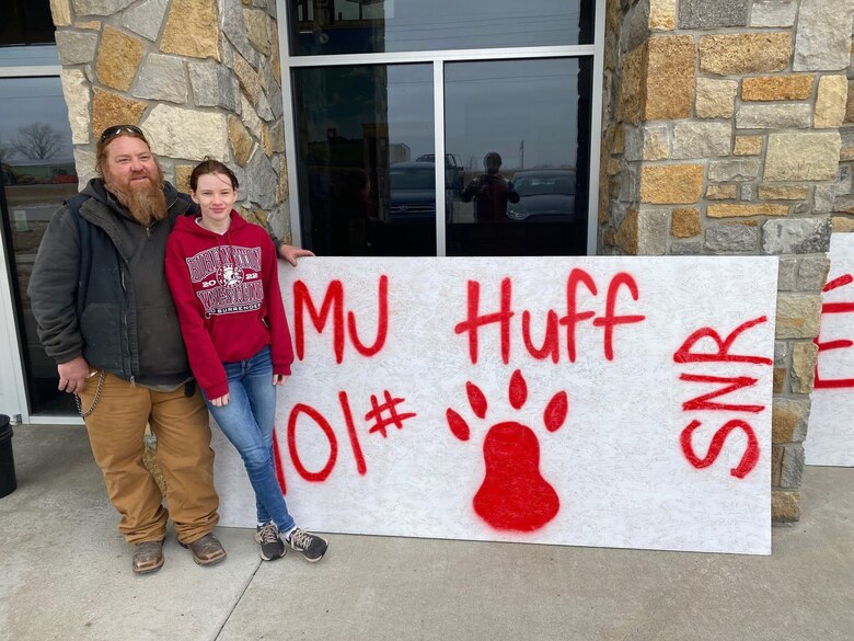 Poolee Marijane D. Huff, a Burlington, Kansas native, poses with her father, Matt Huff, in front of a poster made to show support of her during a wrestling meet. Huff, a state ranked wrestler and avid volunteer in her community, placed second in her state wrestling championship this year and is the second female wrestler in her school to win one hundred matches. Huff joined the Marine Corps Delayed entry program May 11, 2021 and is scheduled to depart for recruit training in June 2022.