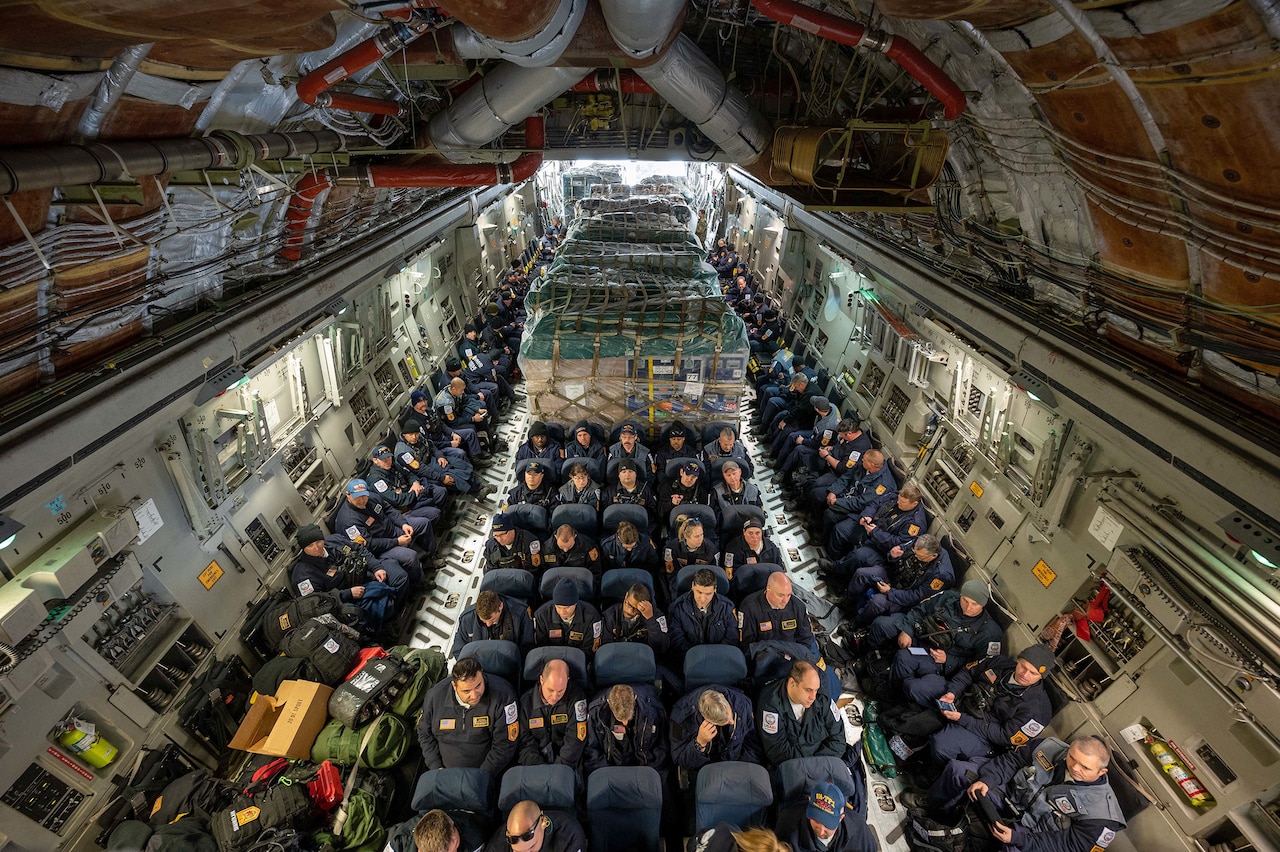 Interior view of an aircraft filled with people and cargo.
