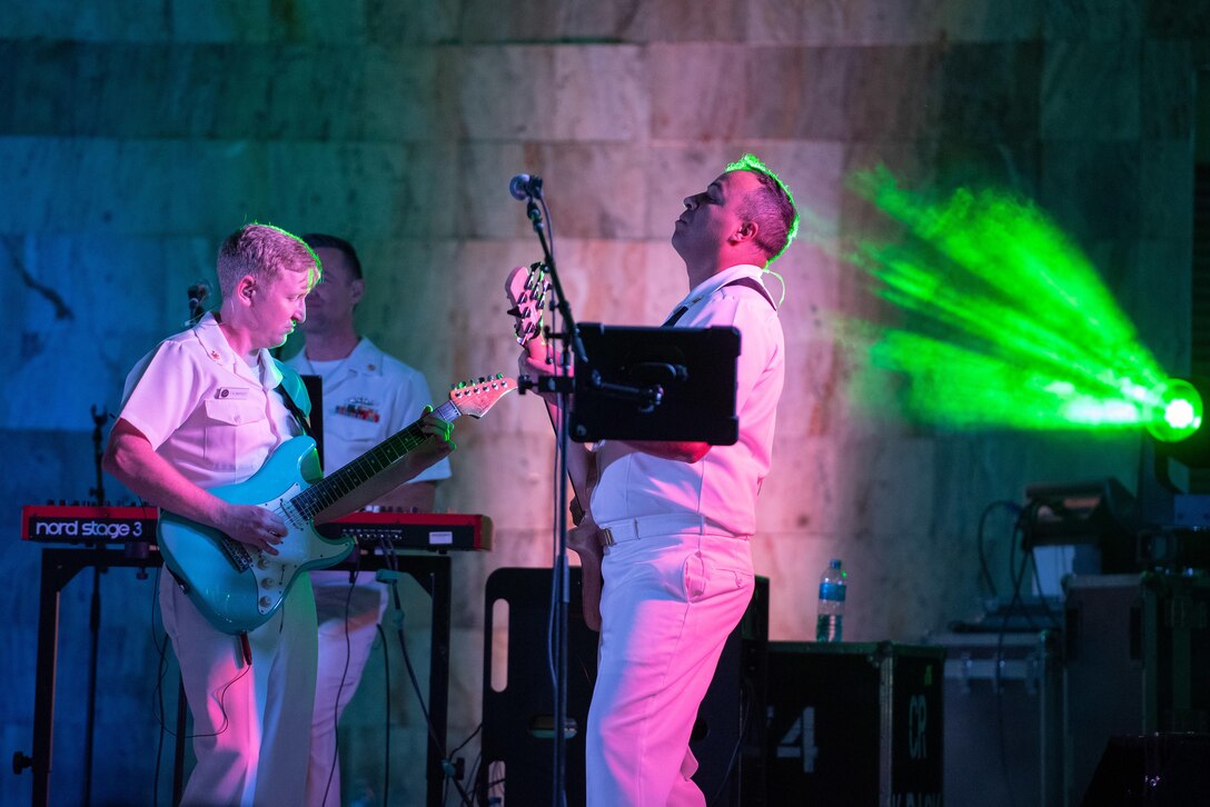 Three sailors are shown playing instruments during a performance.