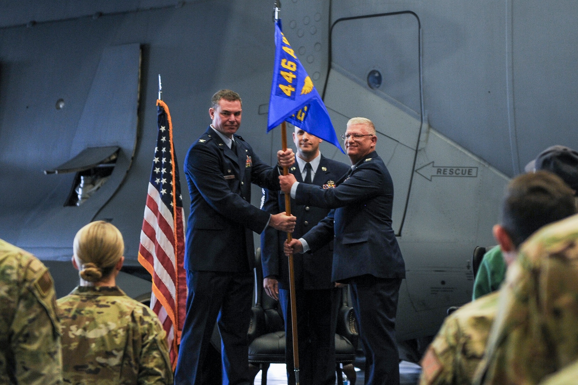 Col Scott Meyer pass blue 446 Airlift Wing guidon to Col Robert Griffith in front of a C-17 Globemaster III