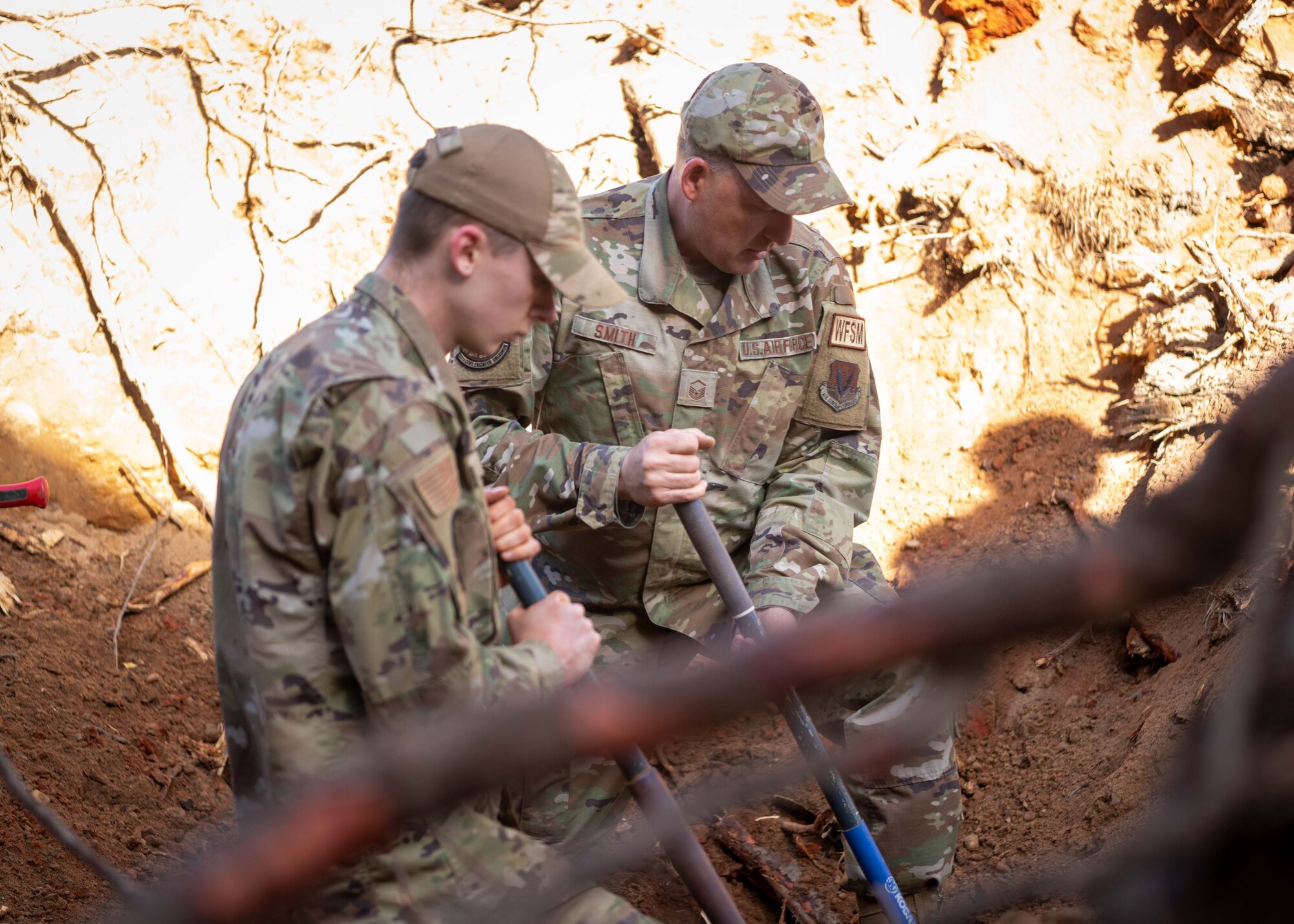 Two Airmen excavate a sewage line outside of the Carolina Skies Club.