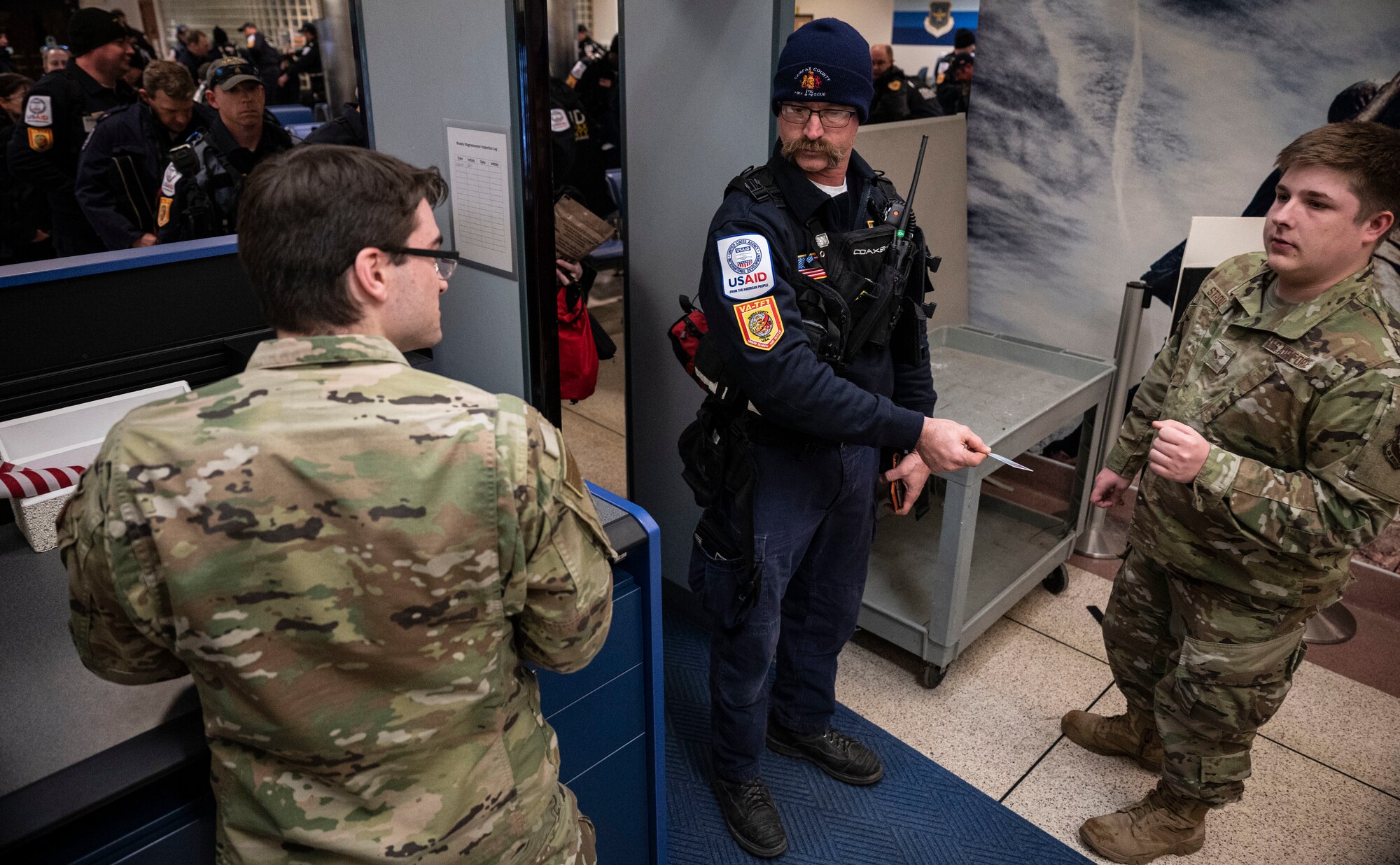 Airman Donovan Harris, left, and Airman 1st Class Jayden Stroup, right, 436th Aerial Port Squadron passenger service representatives, verify names of Urban Search and Rescue personnel from Fairfax County, Virginia, prior to boarding a C-17 Globemaster III on Dover Air Force Base, Delaware, Feb. 7, 2023. The U.S. Agency for International Development (USAID) is mobilizing emergency humanitarian assistance to respond to the devastating impacts in Türkiye following the worst earthquake to hit the region in almost a century. (U.S. Air Force photo by Staff Sgt. Marco A. Gomez)
