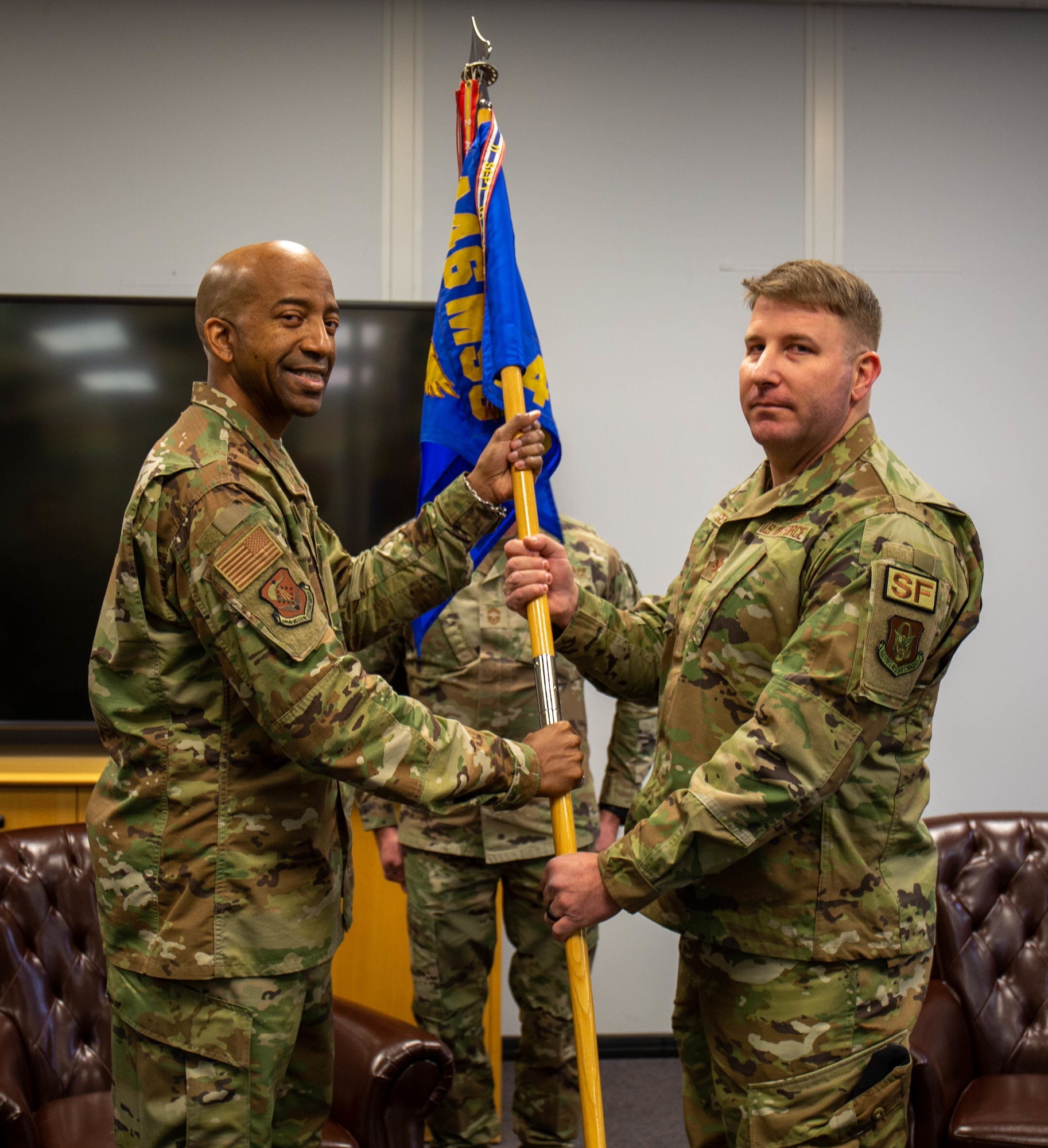 Colonel Sherard Dorroh passes a blue 446 AW guidon flag to Major Andrew Geer.