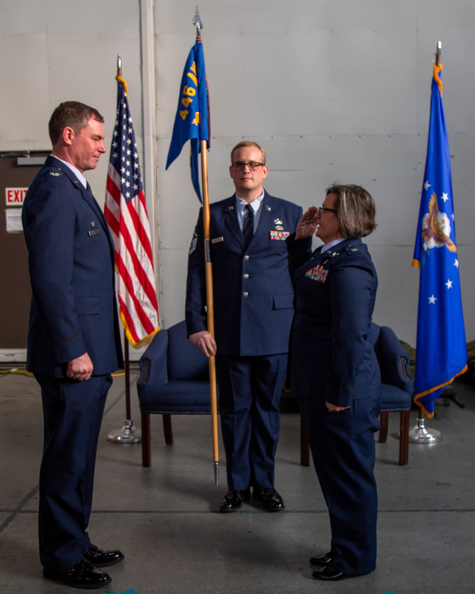Lt Colonel Anniesa Selimos salutes Colonel Scott Meyer in front of the blue 446 Airlift Wing guidon flag.