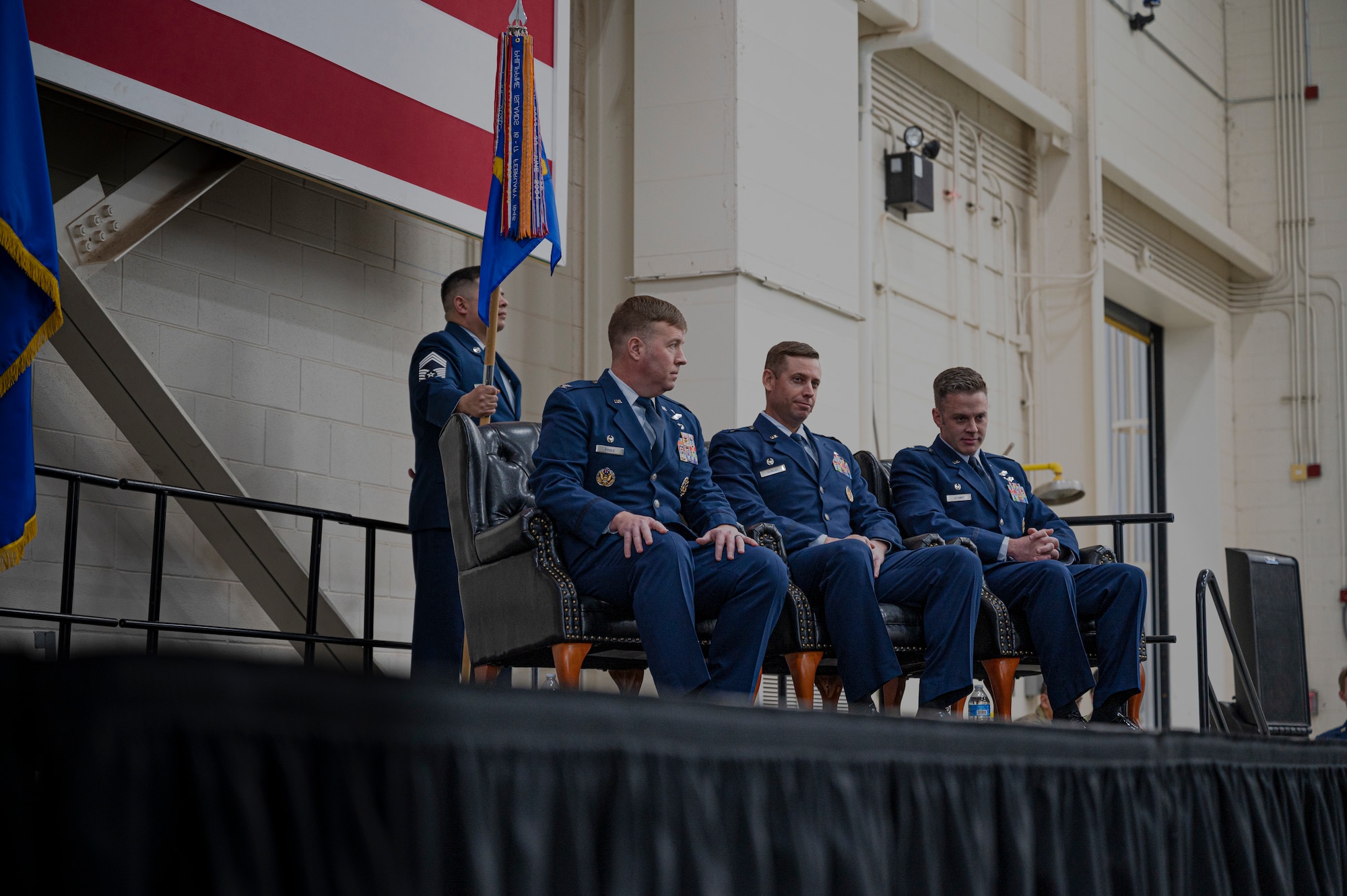 Col. John Poole, 317th Operations Group commander, Lt. Col. Samuel Dunlap, outgoing 40th Airlift Squadron commander, and Lt. Col. Sean Stumpf, incoming 40th AS commander, sit on stage during the 40th AS change of command ceremony at Dyess Air Force Base, Texas, Feb. 3, 2023. The 40th AS supports theater commanders' requirements with combat-delivery capability through tactical airland and airdrop operations as well as humanitarian efforts and aeromedical evacuation. (U.S. Air Force photo by Senior Airman Colin Hollowell)