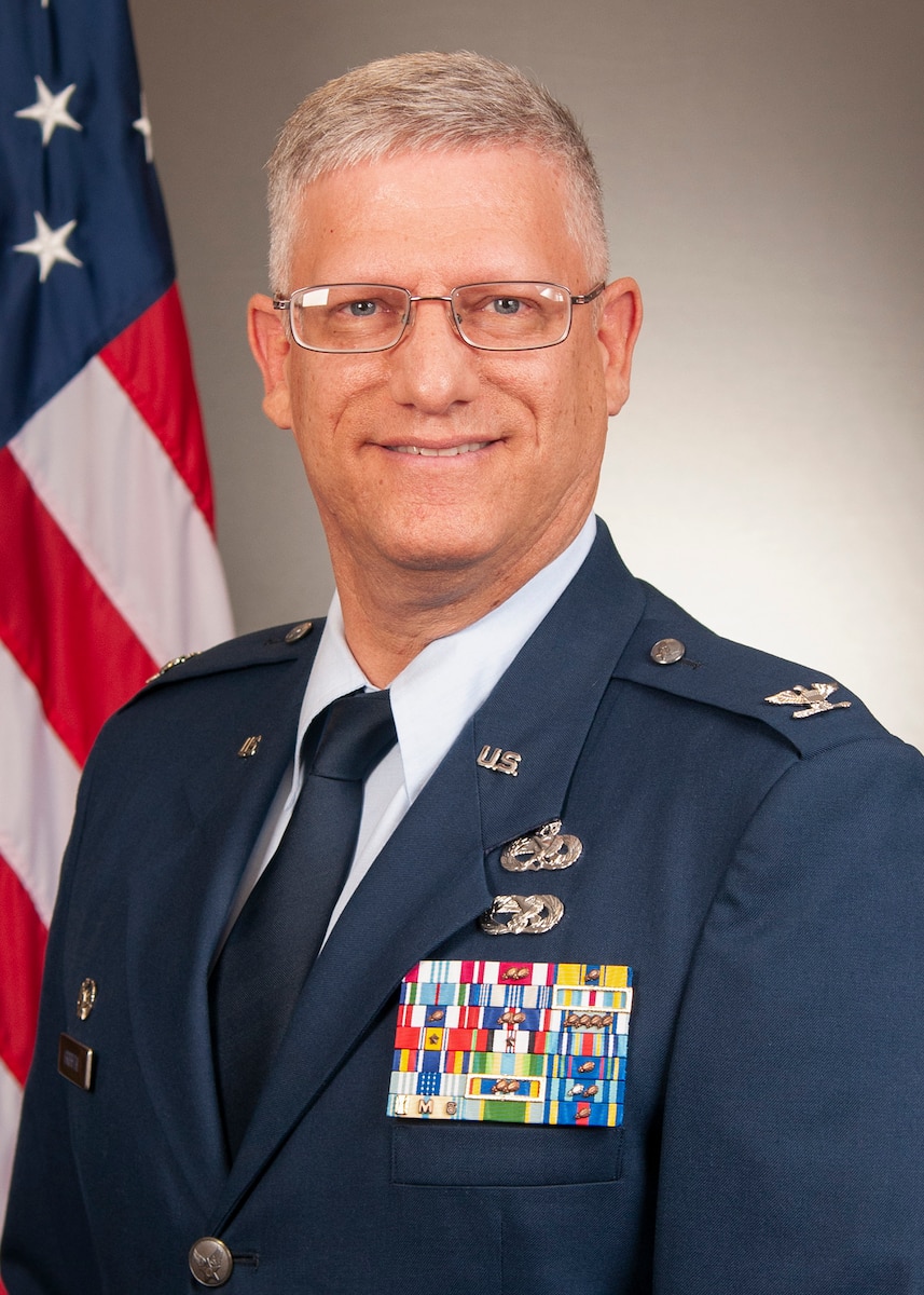 Photo of Colonel Griffith in front of grey backdrop with American flag.