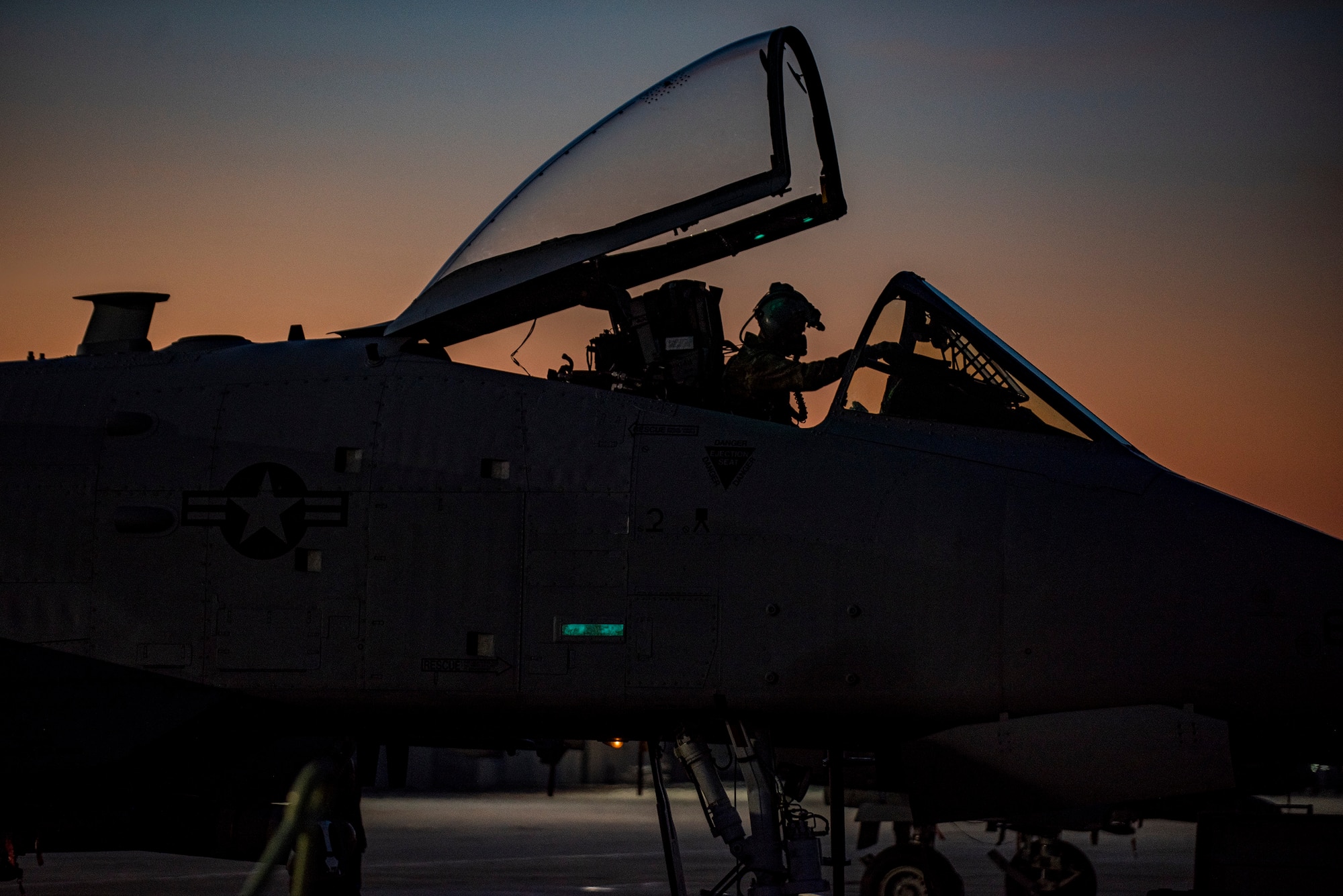 An A-10 prepares to take off for a night and is silhouetted with a sunset