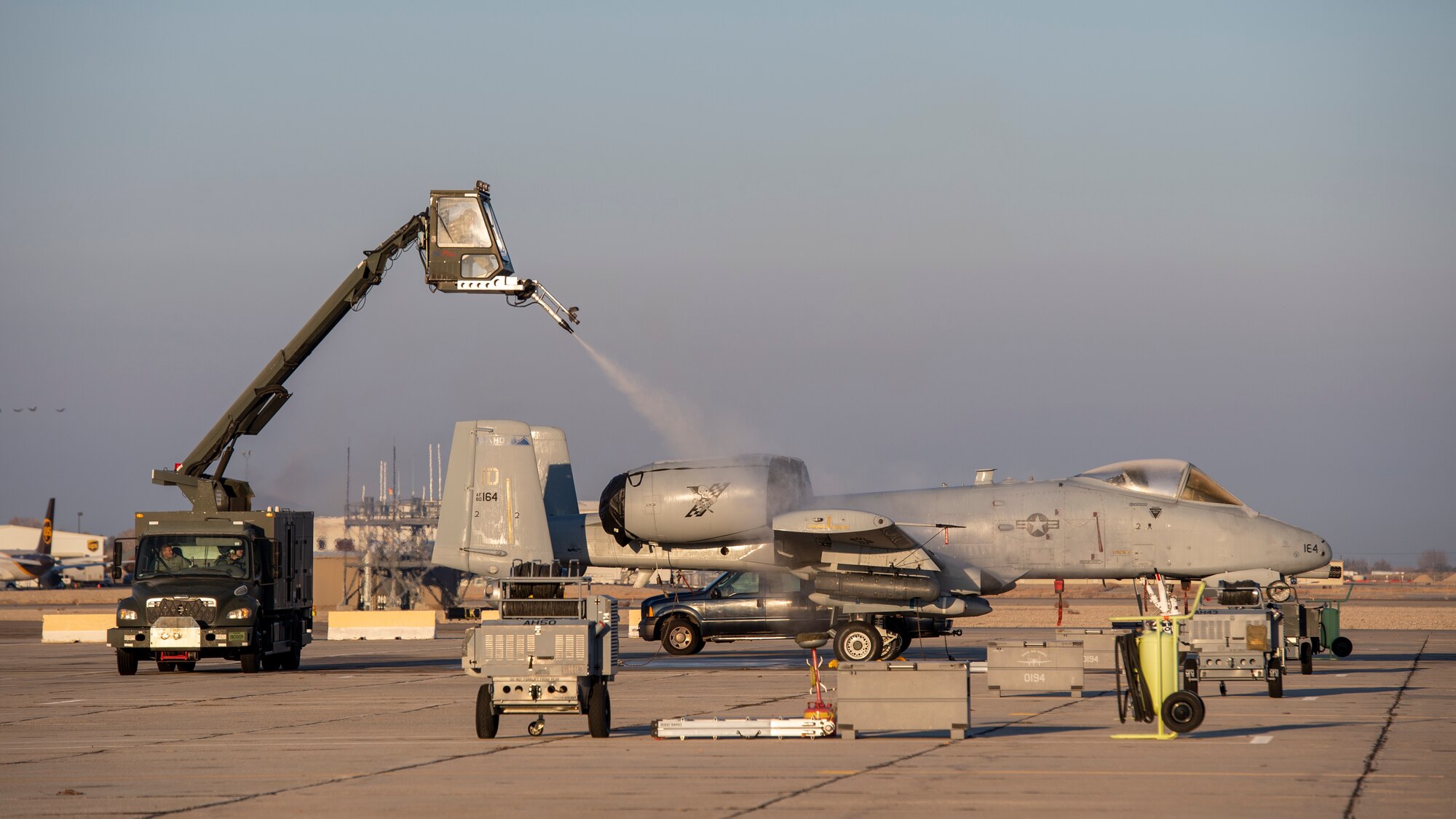 An A-10 Thunderbolt II is being deiced on a flightline.