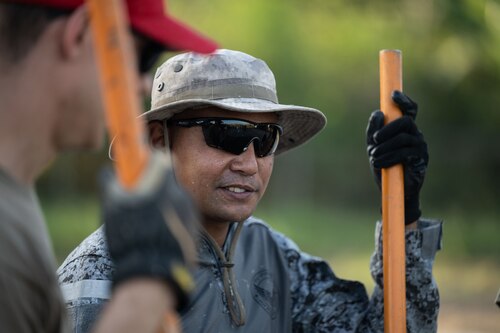 A member of the Philippine Air Force talks with a member from the 819th RED HORSE Squadron while waiting to pour concrete as part of a Field Training Event at Basa Air Base, Philippines, January 25, 2023. Events like this show the U.S. Air Force commitment to improving the defensive capabilities of its Allies and partners, and international Airmen are the backbone of those military-to-military partnerships. (U.S. Air Force photo by Tech. Sgt. Hailey Haux)