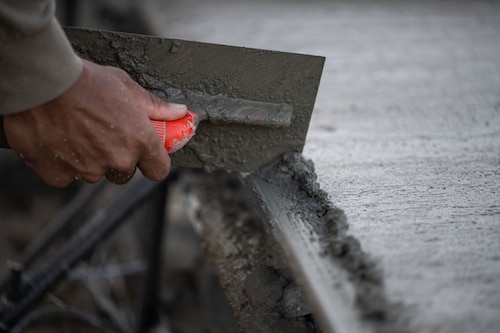 Senior Airman Keith Milton, 819th RED HORSE Squadron Pavements and Equipment operator, edges concrete that was poured as part of a Field Training Event at Basa Air Base, Philippines, January 25, 2023. The two teams poured roughly 220 cubic yards of concrete over the course of their time together, learning how each team operates and improving processes a little at a time. (U.S. Air Force photo by Tech. Sgt. Hailey Haux)