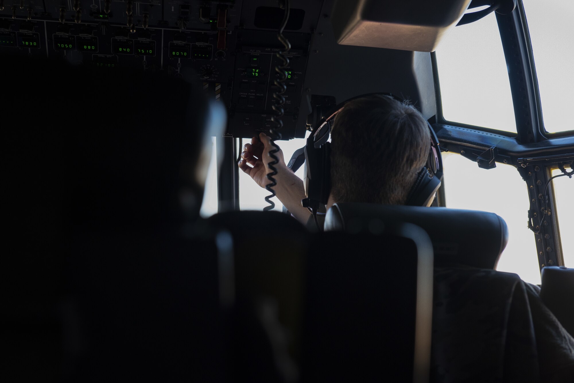 A man adjusts a knob on a C-130J while he pilots the aircraft