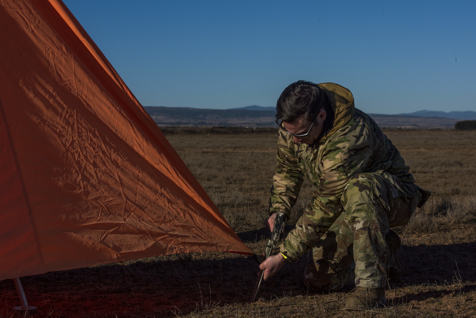 A man uses a hammer to put a stake into the ground.