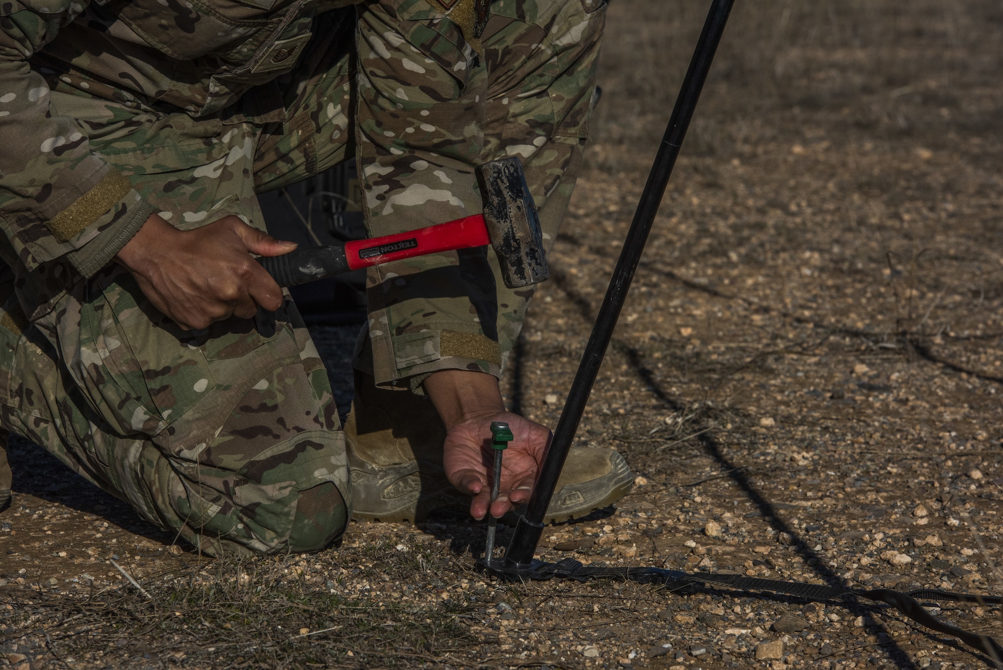 A man uses a hammer to put a stake in the ground.