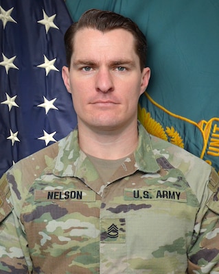 Male Soldier standing in front of two flags.