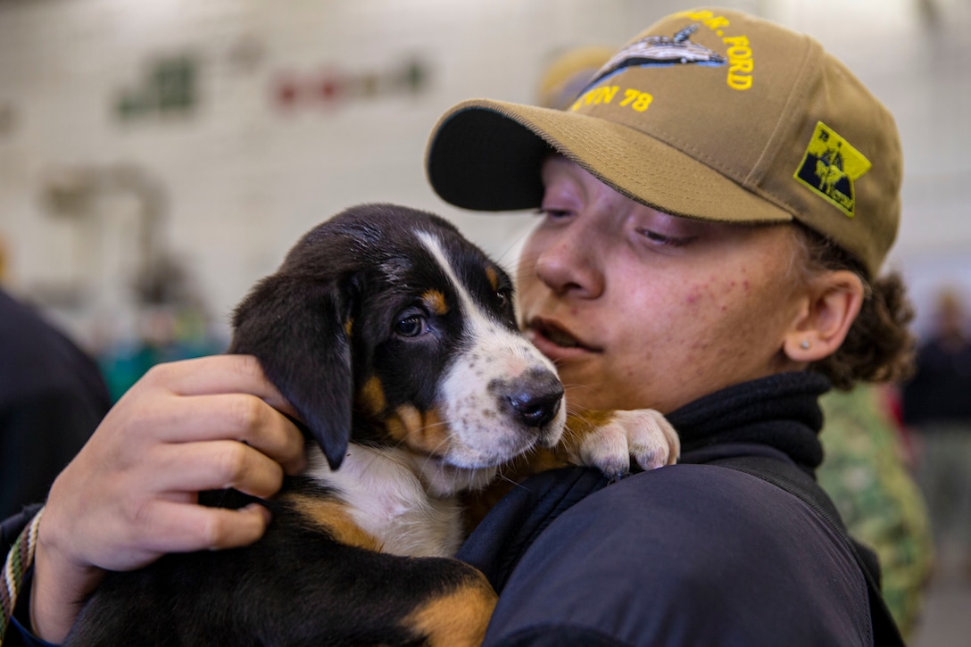 A sailor holds a puppy.