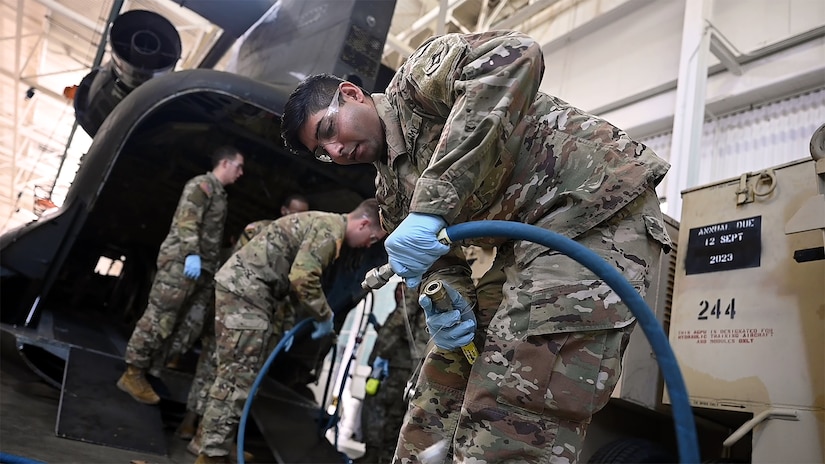 U.S. Army Spc. Richard Maraj, 1st Battalion, 210th Aviation Regiment, 15H student, connects hydraulic cables between a Boeing CH-47 Chinook helicopter simulator and an aviation ground power unit during hands-on training to become an aircraft pneudraulic repairer at Joint Base Langley-Eustis, Virginia, January 23, 2023. During the 14 week-long course, students will learn to perform maintenance on aviation pneudraulic systems such as landing gear, rudders, and brakes. (U.S. Air Force photo by Abraham Essenmacher)