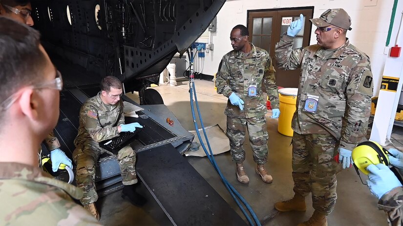 U.S. Army Pfc. Justin Mayhew, left, 1st Battalion, 210th Aviation Regiment, 15H student, reviews hydraulic procedures from the rear ramp of a Boeing CH-47 Chinook helicopter simulator, with guidance from instructors Sgt. Shawn Wright and Staff Sgt. Raul Canedo, Charlie Company, 1st Battalion, 210th Aviation Regiment, during hands-on training to become an aircraft pneudraulic repairer at Joint Base Langley-Eustis, Virginia, January 23, 2023. During the course, students will learn to diagnose and troubleshoot mechanical components associated with pneudraulic systems in aircraft. (U.S. Air Force photo by Abraham Essenmacher)