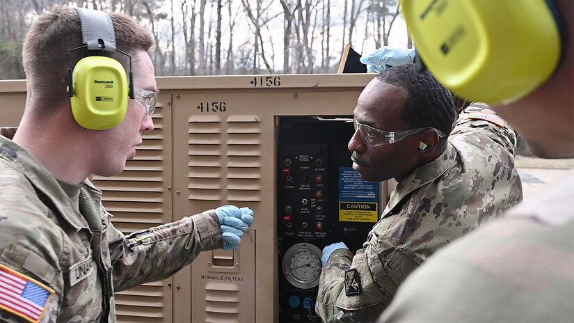 U.S. Army Pfc. Nicholas Unangst, left, 1st Battalion, 210th Aviation Regiment, 15H student, asks Sgt. Shawn Wright, Charlie Company, 1st Battalion, 210th Aviation Regiment, instructor, a question about the aviation ground power unit during hands-on training to become an aircraft pneudraulic repairer at Joint Base Langley-Eustis, Virginia, January 23, 2023. During the 14 week-long course, students will learn to perform maintenance on aviation pneudraulic systems such as landing gear, rudders, and brakes. (U.S. Air Force photo by Abraham Essenmacher)