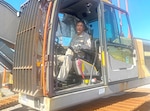 A man poses in the driver seat of a large tractor.